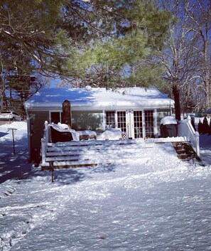 Une maison recouverte de neige, avec un porche, une cheminée et un garage.