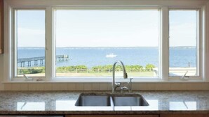 Una cocina con un ventanal amplio que da a una vista al frente marítimo, incluyendo un muelle y el mar.