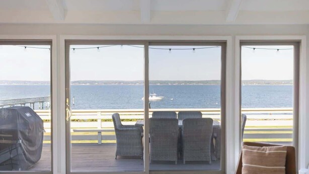 Una habitación con vista al mar, una parrilla y una terraza con sillas.