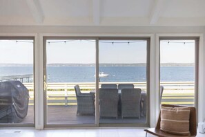 Una habitación con vista al mar, una parrilla y una terraza con sillas.