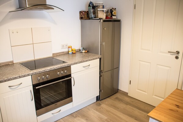 A kitchen with white cabinets, a stainless steel oven, a built-in stovetop, and a refrigerator. - Beautiful vacation apartment in the World Heritage region (Trechtingshausen)