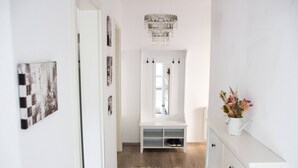 Un couloir avec un banc blanc, un miroir et un vase rempli de fleurs.