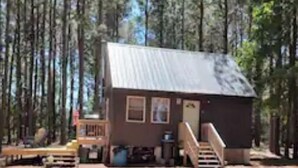 A small cabin with a metal roof, a porch, and a staircase leading to the entrance. - Awesome private off grid cabin with creek view. (Onancock)