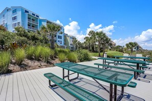 Relax on the outdoor deck with picnic tables amidst lush vegetation and a tropical ambiance.