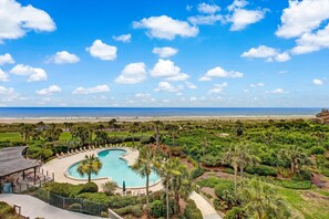 Relax by the resort's large, curved pool surrounded by lush greenery and palm trees.