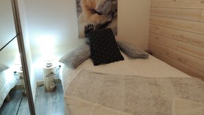 A bedroom with a bed, pillows, a blanket, a wooden headboard, and a wall-mounted picture of a bear. - Studio for 6 with terrace and private parking (Valloire)