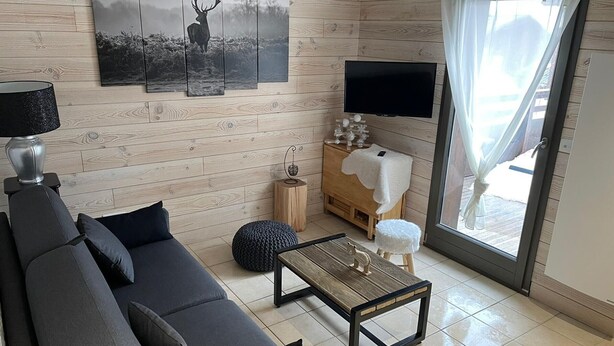 A modern living room with a sofa, coffee table, and artwork on the wall. - Studio for 6 with terrace and private parking (Valloire)