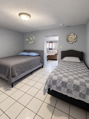Quarto com duas camas, uma luminária no teto e um objeto decorativo na parede.