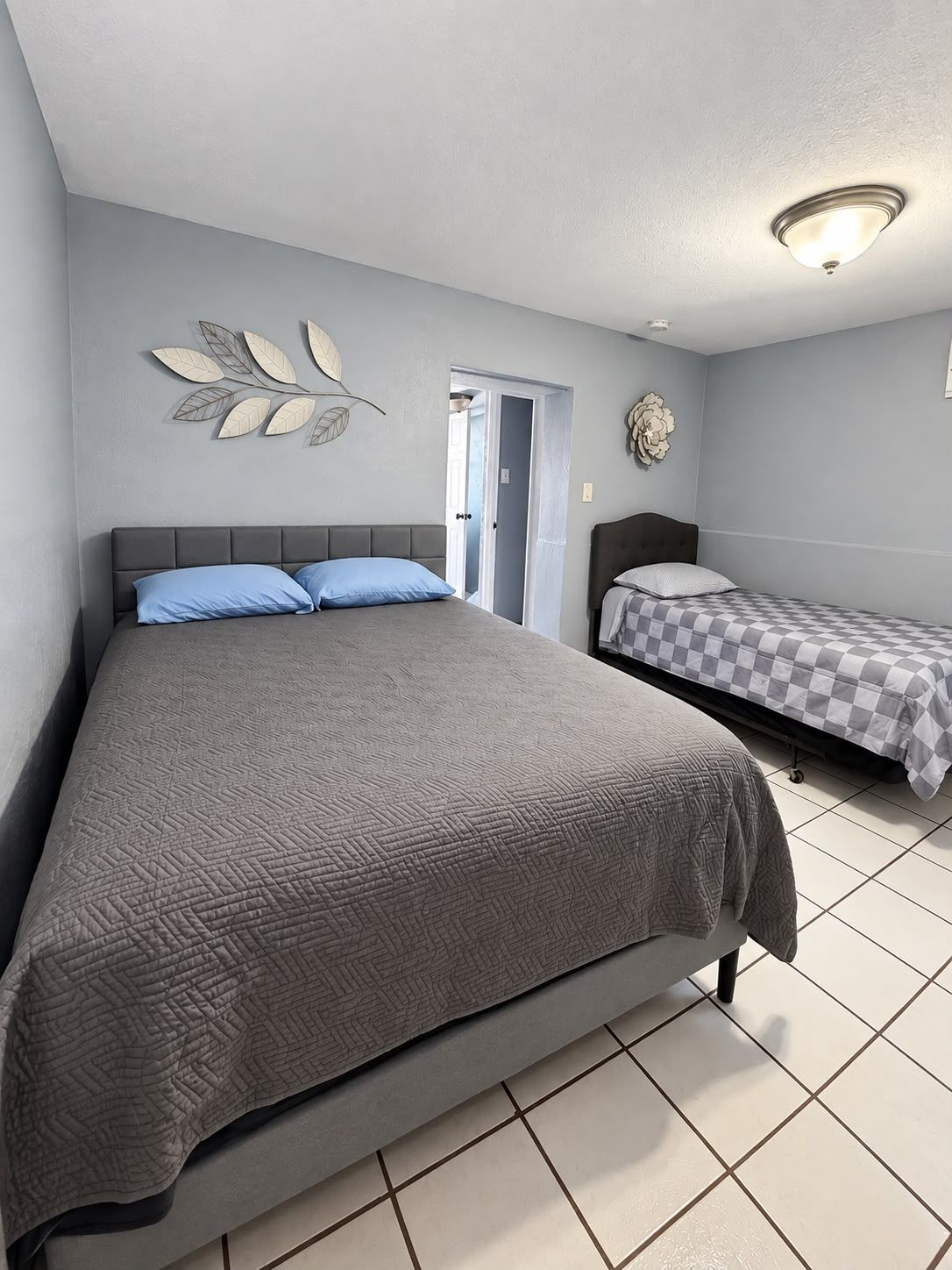 A bedroom with a large bed, a smaller bed, and a door leading to another room.