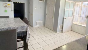 A kitchen with a dining table and chairs, a refrigerator, and a window with a view. - Del Sol Medical Center Gem (El Paso)