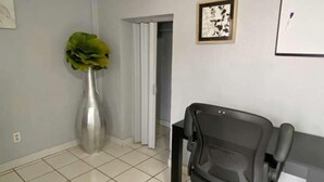 A room with a black office chair, a large potted plant, a framed picture on the wall, and a tiled floor. - Del Sol Medical Center Gem (El Paso)