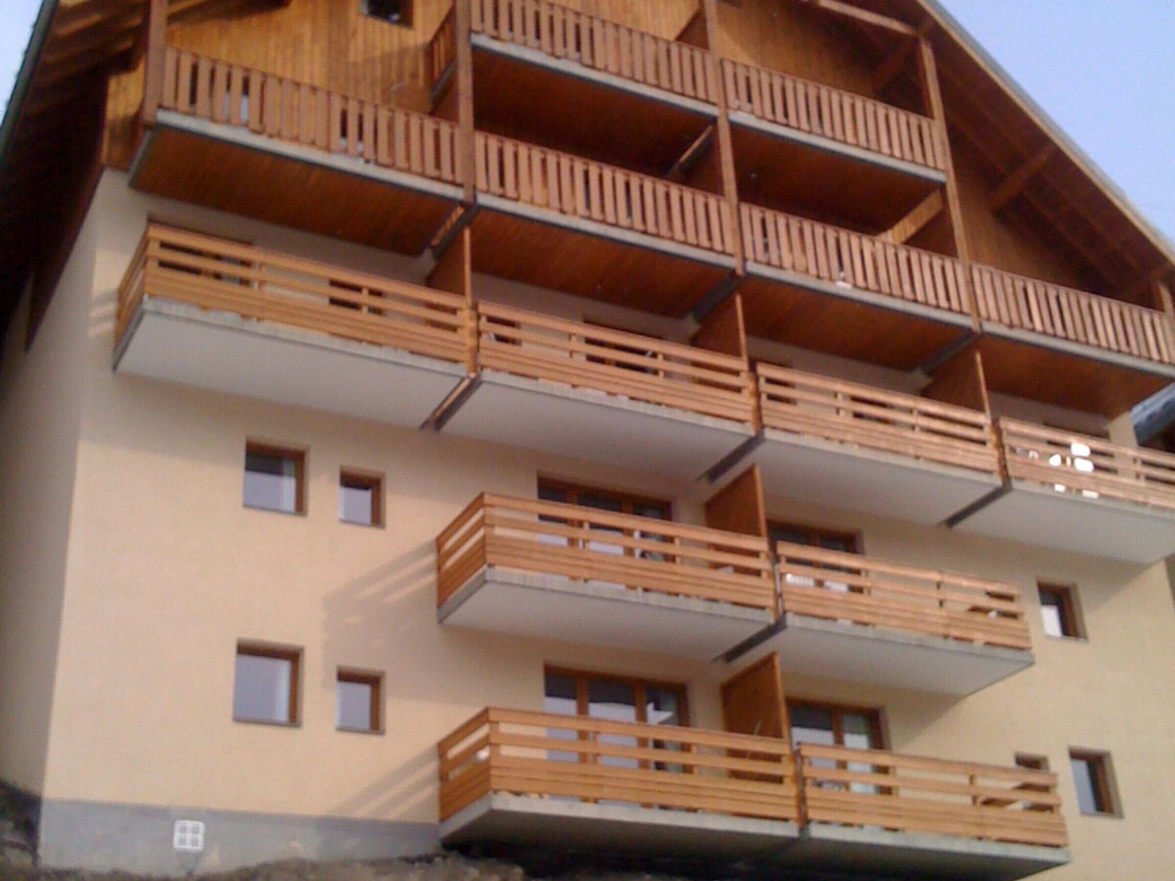 A multi-story building with wooden balconies and multiple windows.