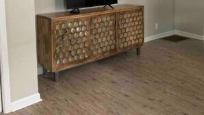 A room with a wooden cabinet, a flat-screen TV on top, and a light-colored floor. - Big Blue House Apt 1 (Pikeville)