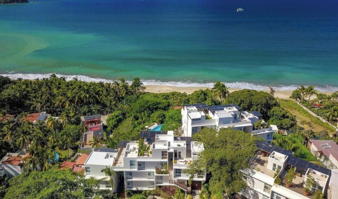 Un quartier résidentiel en bord de mer, avec des maisons modernes, une plage et une vue dégagée sur l’océan.