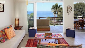 A living room with a sofa, a coffee table, and a view of the ocean.