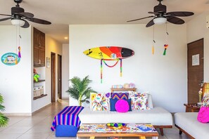 A modern living room with a sofa, a coffee table, and a surfboard decoration on the wall.