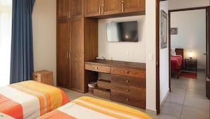 Ein Schlafzimmer mit zwei Betten, einem Holzschrank, einem Fernseher und einem kleinen Tisch.