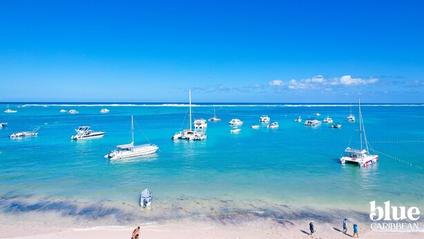 Une plage où plusieurs bateaux sont amarrés et où des personnes se promènent sur le rivage.