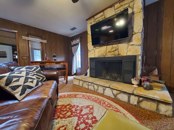 A cozy living room with a stone fireplace, leather sofa, and a flat-screen TV mounted above it. - Cozy 3 bedroom house with fireplace in beautiful Ruidoso (Ruidoso)