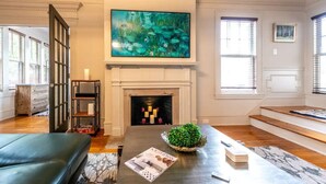 Un salon avec une cheminée, un grand tableau, un canapé et une table basse.