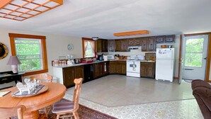 Una cocina con armarios de madera, una estufa blanca y una zona de comedor con mesa y sillas.