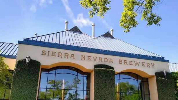 Sierra Nevada -panimon ulkonäkö: metallikatto, suuret ikkunat ja vihreää kasvillisuutta rakennuksen sivuilla.