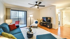 A modern living room with a sofa, coffee table, TV, and a ceiling fan. - Walkable Location: Phoenix Apt w/ Pool Access! (Phoenix)