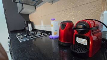 Une cuisine équipée d’une cuisinière à gaz, d’une machine à café rouge et d’un distributeur d’essuie-tout.