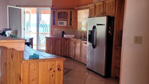 A kitchen with wooden cabinets, a stainless steel refrigerator, a microwave, and a sink.