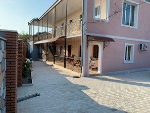Ein mehrstöckiges Gebäude mit überdachter Außenbereiches, einer Treppe und einer sichtbaren Klimaanlage.