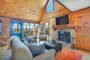 Cozy cabin interior with a seating area, fireplace, and large window.