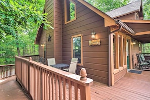 Relax on the Windsong deck, where a table and chairs invite dining and socializing amidst the forest surroundings.