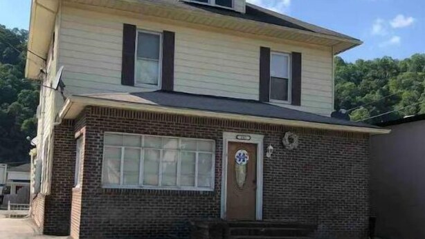 A two-story house with a brick facade, a front porch, and a small attached garage. - The   Nook (Pikeville)