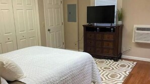 A bedroom with a bed, a dresser, a television, and a patterned rug. - The   Nook (Pikeville)