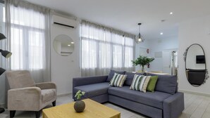 A modern living room with a grey sofa, a round mirror, and a wooden coffee table.