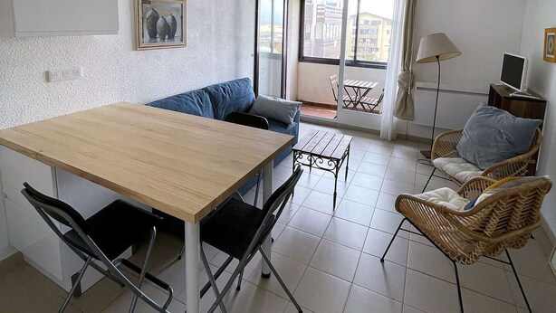 A small, bright room with a wooden table, black chairs, a blue sofa, and wicker chairs. - Seignosse Ocean, beautiful apartment with SEA VIEW, close to the beach and town center, sleeps 4 (SEIGNOSSE)