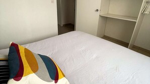 A bedroom with a bed, a colorful pillow, a wardrobe, and a door leading to a hallway. - Seignosse Ocean, beautiful apartment with SEA VIEW, close to the beach and town center, sleeps 4 (SEIGNOSSE)