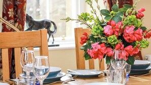 A dining table set with plates, glasses, and a vase of flowers. - Clocktower - Culzean Castle (Maybole)