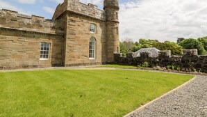 A historic stone building with a turret and arched windows, surrounded by a well-maintained lawn and garden. - Clocktower - Culzean Castle (Maybole)