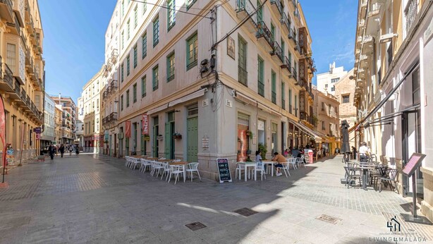 Une rue bordée de terrasses, des immeubles dotés de balcons et un ciel dégagé.