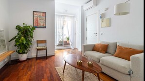 Un salon moderne avec un canapé, une table basse, un fauteuil et une grande plante en pot.