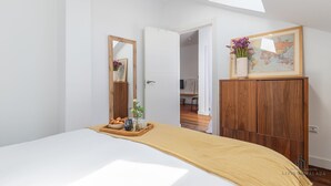 Une chambre à coucher avec un lit, une commode en bois, un miroir, un plateau avec des collations et une carte du monde accrochée au mur.
