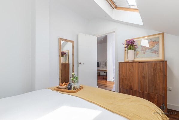 A bedroom with a bed, a wooden dresser, a mirror, a tray with snacks, and a world map on the wall.