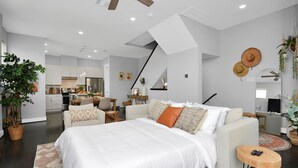 Quarto moderno com uma cama grande, um sofá e uma área de refeições ao fundo.