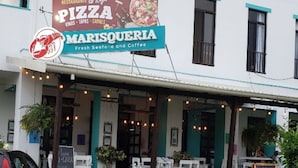 A restaurant named 'Marisqueria' with a signboard advertising pizza, seafood, and coffee. - Cozy Iguana Apartmentos 3 (Esterillos Oeste)