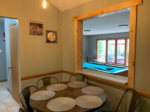 Un comedor con mesa de billar, una ventana con vistas al exterior y una puerta que da a otra habitación.