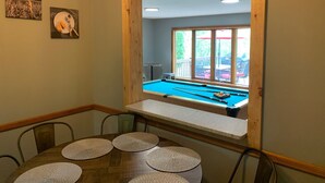Een eetgedeelte met een pooltafel, een raam met uitzicht op de omgeving en een tafel met placemats.
