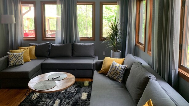 Een moderne woonkamer met een grijze modulaire bank, een ronde salontafel en een potplant.