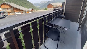 A balcony with a table and chairs, overlooking a parking area and a mountain landscape. - Veronica n°53: T2 with mountain corner (Châtel)