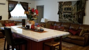 Een eetgedeelte met een centraal eiland, stoelen, een bank en een schilderij aan de muur.